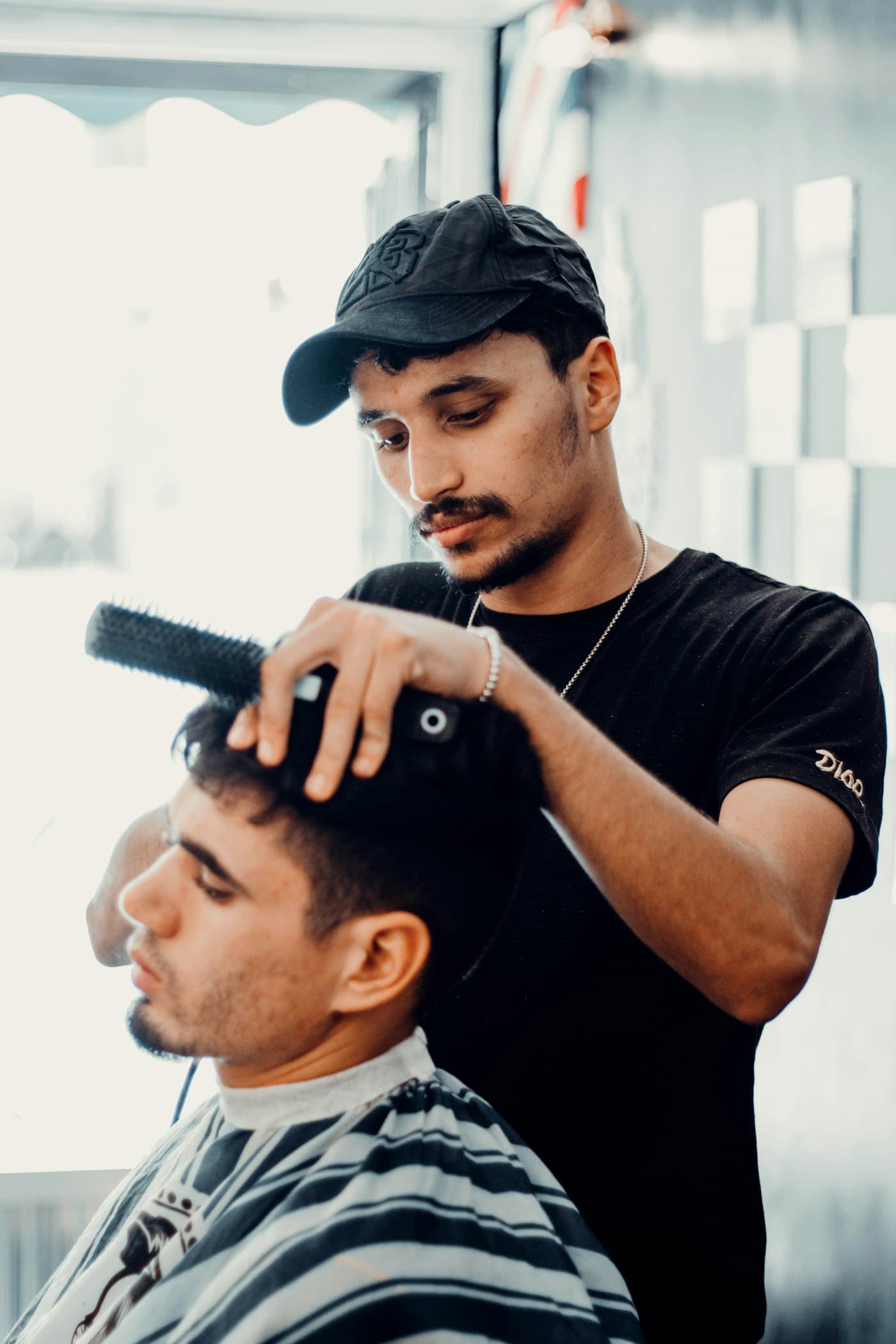 Barbier stylet het haar van een klant bij het raam