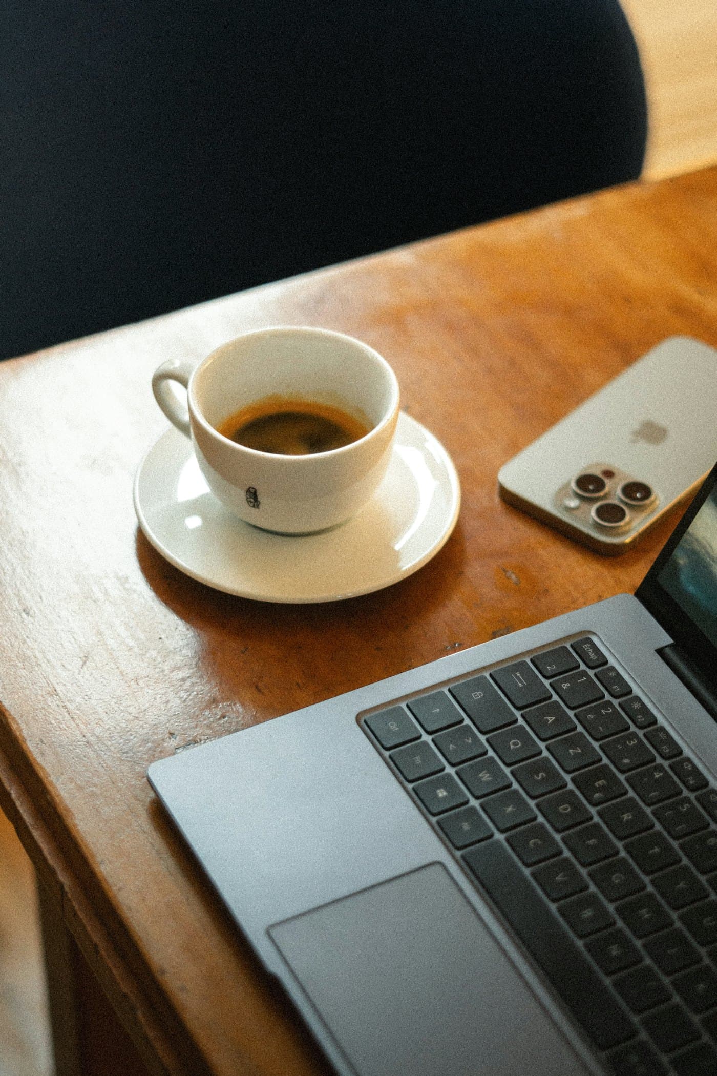 Telefoon en laptop met een kop koffie op een houten tafel